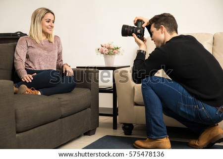Profile view of a pretty young woman posing and smiling for a photographer during a photo shoot at home