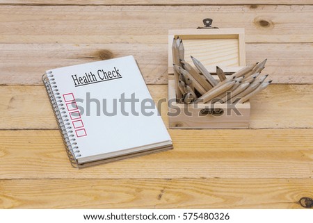 notebook and word, pencils placed in wooden barrels and wood table background