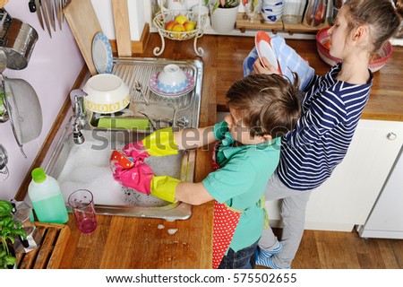 Two young caucasian children are doing the dishes in kitchen at home Royalty-Free Stock Photo #575502655