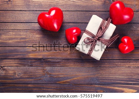 Gift box with present  and red  hearts on vintage wooden background. Selective focus. Place for text. Toned image.
