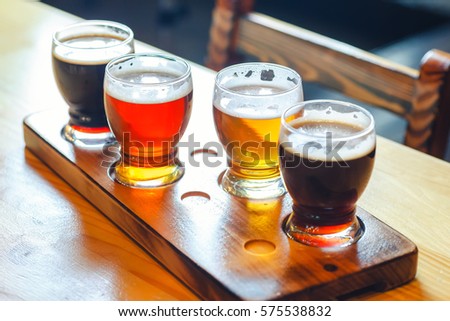 Flight with various types of craft beer in small glasses on a wooden table in a pub Royalty-Free Stock Photo #575538832