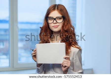 business woman with glasses wearing a white shirt against the backdrop of the city notebook in the hands..