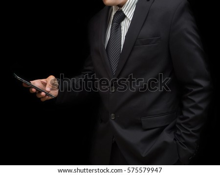 A businessman hold the mobile phone on black background.