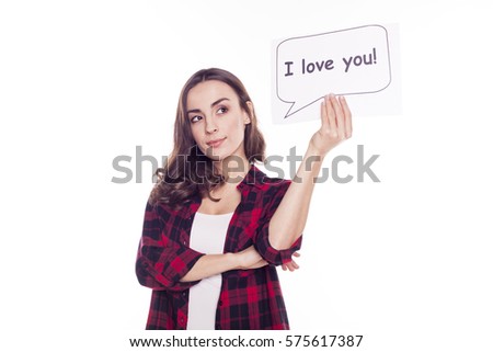 Young beautiful girl in a red checked shirt smiles and holds in her hands a white paper with an inscription i love you on a white background isolated. With love. The 14th of February.