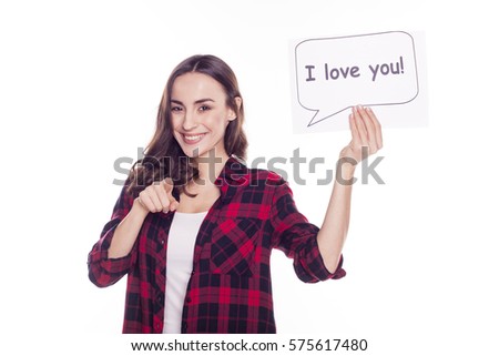 Young beautiful girl in a red checked shirt smiles and holds in her hands a white paper with an inscription i love you on a white background isolated. With love. The 14th of February.