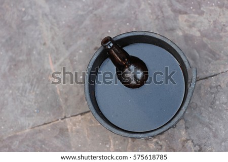 Empty Beer Bottle Partially Submerged in a Bucket full of water