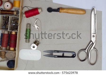 Sewing supplies - the attributes of the master. On the desktop lay a pair of scissors, a box of thread, needles and other tools of a seamstress. There is a free place for text.