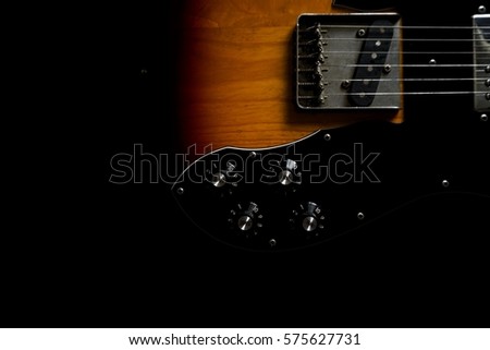 Ash wood texture of six steel strings vintage style sunburst electric guitar on black background, selective focus