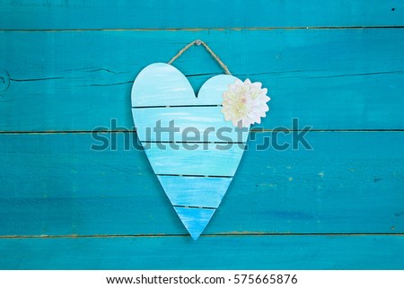 Blank pallet heart sign with spring flower hanging on antique rustic teal blue wood background; Mothers Day and Valentines Day background with painted wooden copy space