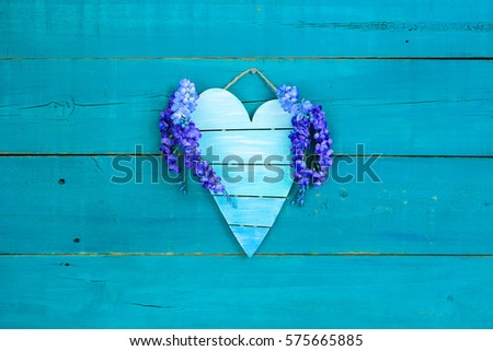 Blank pallet heart sign with purple spring flowers hanging on antique rustic teal blue wood background; Mothers Day and Valentines Day background with painted wooden copy space
