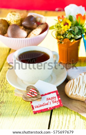 Heart shaped cookies and chocolate candies (big and small as couple), cup of coffee, bouquet of flowers decoration. sunny morning. Romantic breakfast or Valentine's Day Breakfast. Toned image