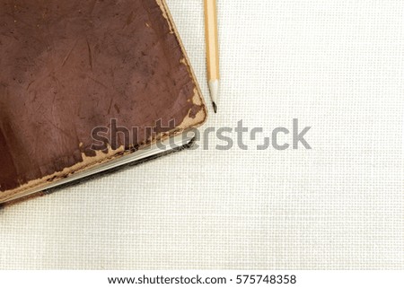 Old leather vintage book with pencil on simple burlap background, space for text