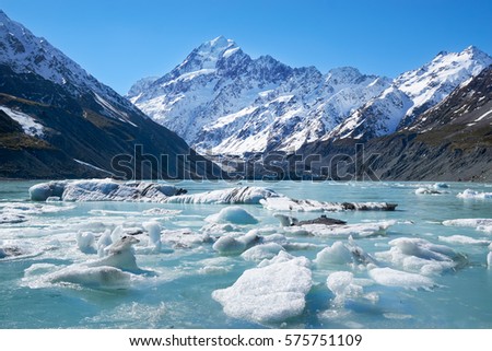 Glacier lake with ice blocks and background of misty Mount Cook shot during early spring Royalty-Free Stock Photo #575751109