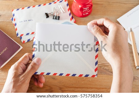 closeup man's hand opening an envelope over desktop