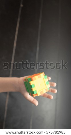 Child's hand holding colorful toy cube