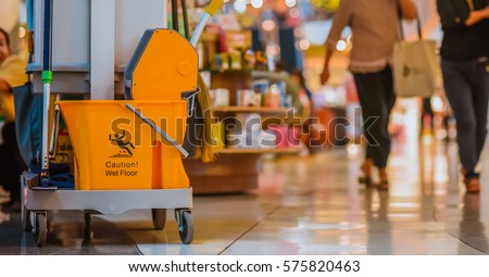 Yellow mop bucket floor cleaning equipment and mops in shopping mall and department store vintage style picture.