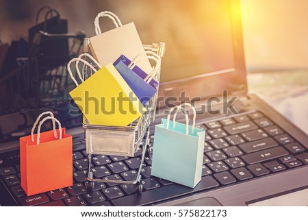 Colorful paper shopping bags in a trolley. Ideas about online shopping addiction. A shopping addict is someone who shops compulsively and who may feel like they have no control over their behavior. Royalty-Free Stock Photo #575822173