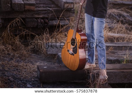 Happy Beautiful Young Woman With Guitar On Railroad Tracks. Copy Space. Pretty smiling young lady holding guitar on railway.