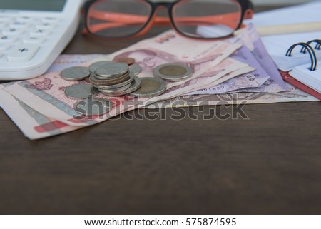 Business on financial report . Closeup coin and banknotes and Calculator , book on wooden background.