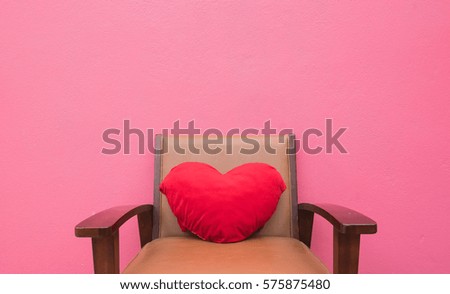 red heart pillow on the chair wall pink background .