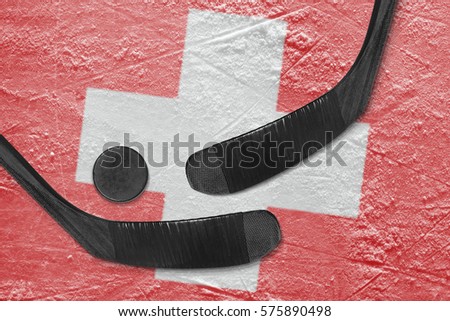 Hockey puck, hockey sticks, and the image of the Swiss flag on the ice. Concept