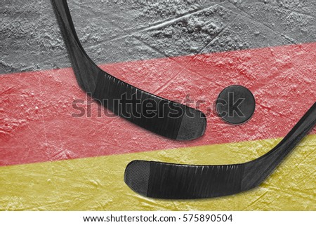 Hockey puck, hockey sticks, and the image of the German flag on the ice. Concept