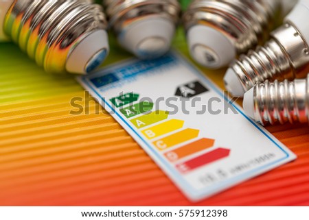 detail of bulb´s screw-threads with energy scale table on colorful background Royalty-Free Stock Photo #575912398