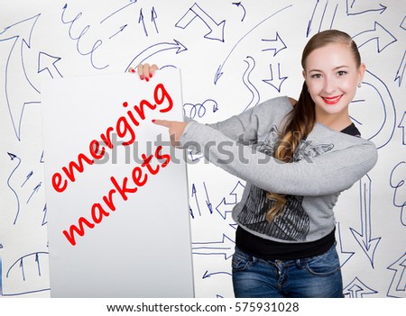 Young woman holding whiteboard with writing word: emerging markets. Technology, internet, business and marketing.