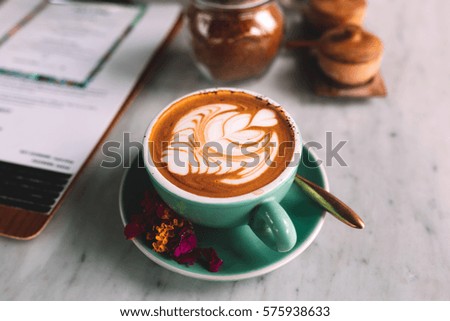A blue cup of coffee with jar of sugar on a marble table