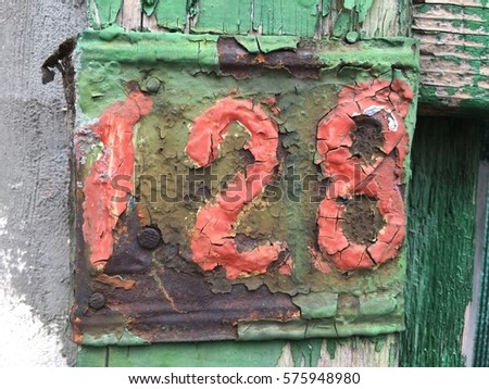 Vintage grunge square metal rusty plate of number of street address with number 128 closeup