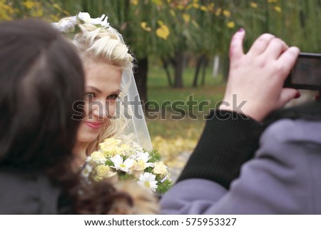 wedding. young and beautiful bride photograph girlfriend on a cellphone