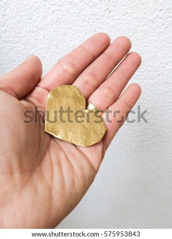 Paper gold heart on hand on white background. Happy valentines day
