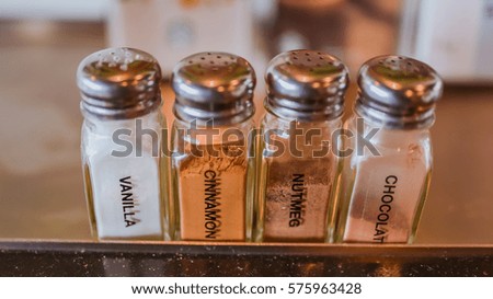 A vanilla powder, cinnamon powder, nutmeg powder and chocolate powder in glass bottle in vintage style picture.
