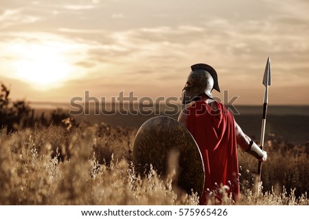 Warrior wearing iron helmet and red cloak. Royalty-Free Stock Photo #575965426