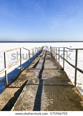 Amazing view of pier in a winter. Landscapes of sea in snow. floating ice. Beautiful winter morning. Winter fairy tail on the sea.