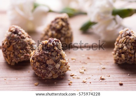 Horizontal photo of few chocolate cupcakes with pistachio nuts and flowers
