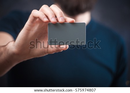 young bearded man holds a business card, business card template closely