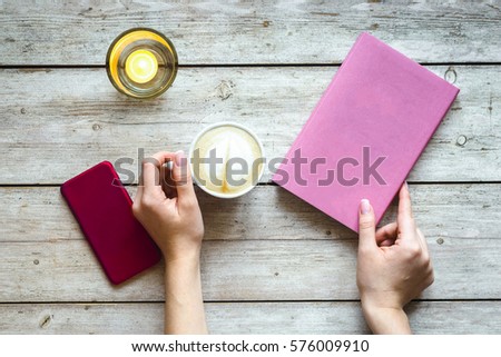 Cup of coffee on wooden table hith hands, top view