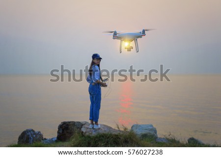 drone flying by the girl in background at sunset scenery