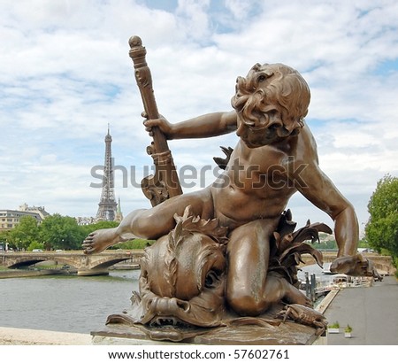 Small statue of a cherub on the Pont Alexandre III with eiffel tower in background in Paris.