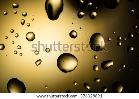 Water drops on glass, crisp and shiny in golden color