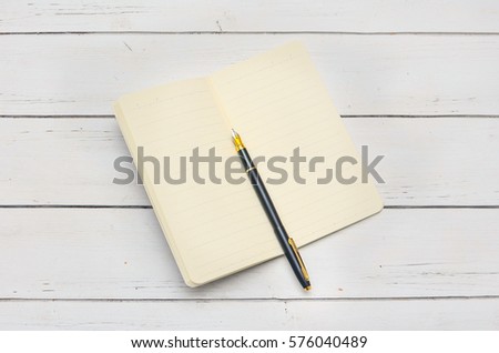Isolated close up Black fountain pen lying on old open notebook diary with stripes on a white background vintage wooden shabby boards