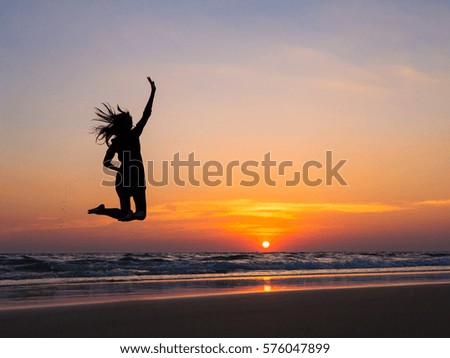 Silhouette of little asian girls jumping on beach in sunset time