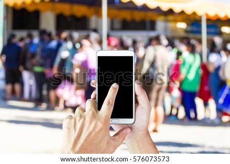 Man use mobile phone, blur image of victims line up to receive food donations as background.