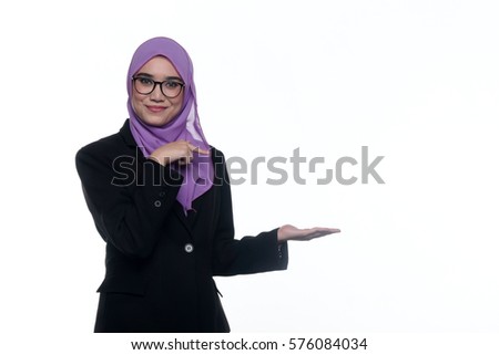 A pretty muslim businesswoman wearing hijab, suit and spectacle use her hands sign towards an empty space beside her, isolated on white background
