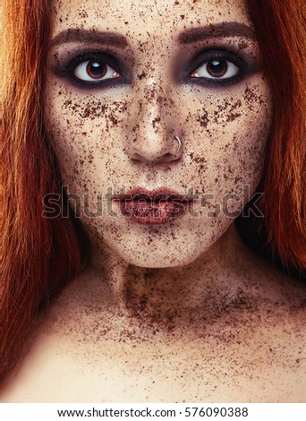 Portrait of young girl with red hair and ground coffee on the face. Photo with art makeup. Mature woman making cosmetic mask. Face scrub. Facial mask. Beauty concept 