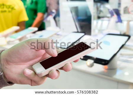 Man use mobile phone, blur image inside mobile shop as background.