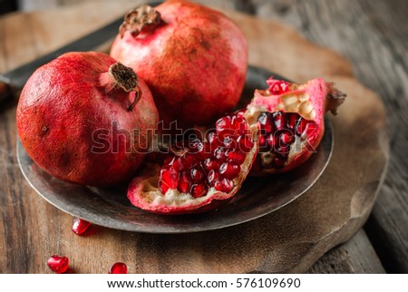 pomegranates on a vintage metal plate on a wooden rustic background. close up and selective focus.