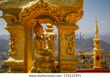 Amazing gold Buddha statue in golden recess made in carved gold with blue sky and mountain background