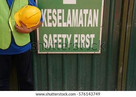 Worker and his safety gear kits on work place with the sign of 'SAFETY FIRST'. Word 'KESELAMATAN' is Malay language which mean 'SAFETY' in English.